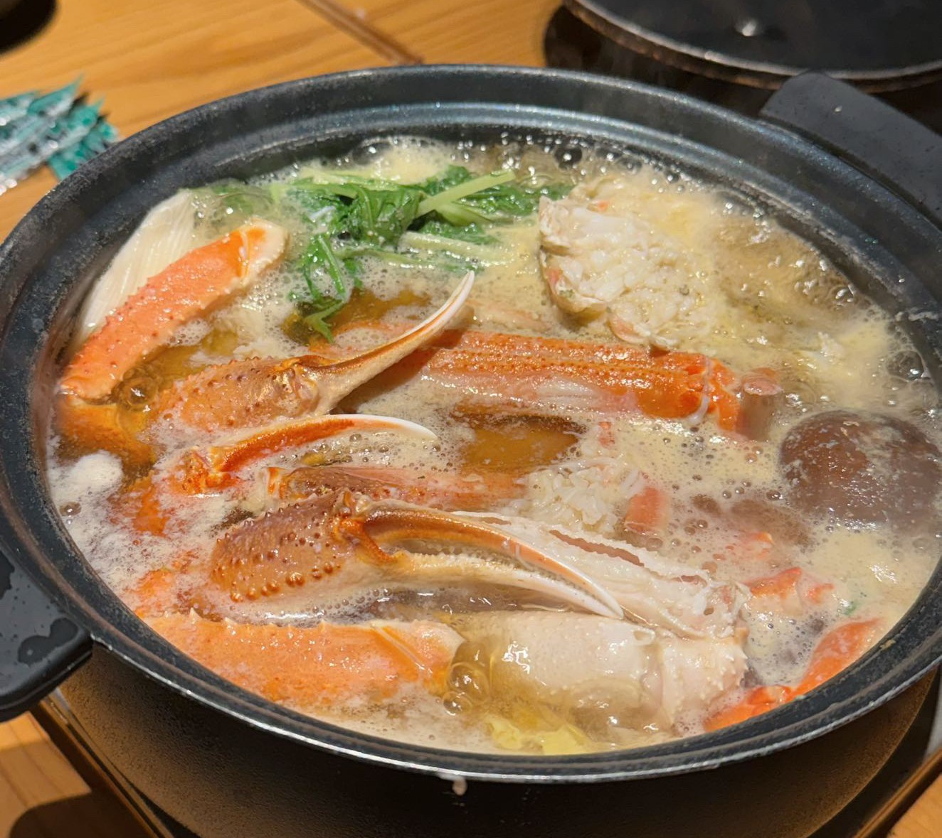 桶に盛られた活ガニと、鍋の野菜・豆腐・卵